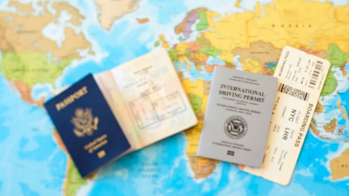 An International Driving Permit booklet next to a passport and plane ticket.